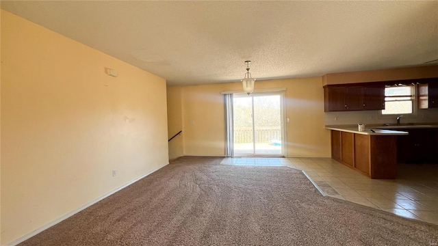 kitchen with a textured ceiling, a wealth of natural light, light colored carpet, and hanging light fixtures