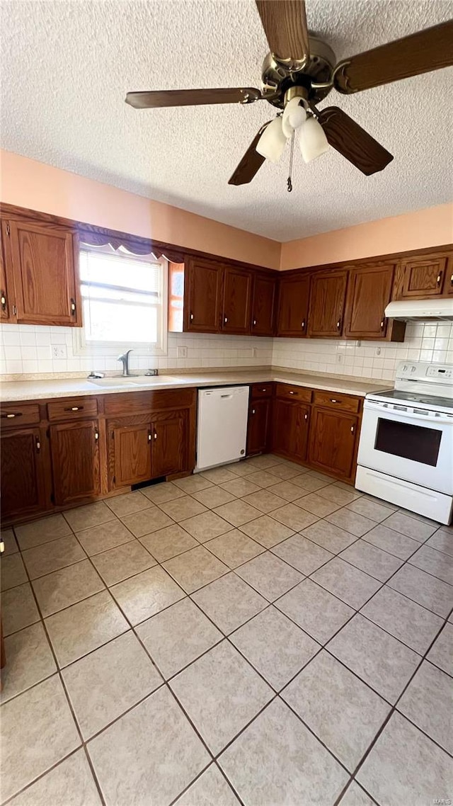 kitchen featuring white appliances, sink, a textured ceiling, ceiling fan, and light tile patterned floors