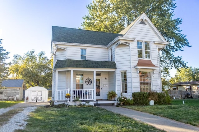 view of front of home featuring covered porch, a storage shed, and a front lawn