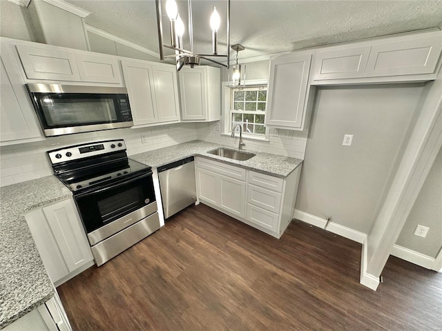 kitchen with lofted ceiling, white cabinets, appliances with stainless steel finishes, pendant lighting, and sink