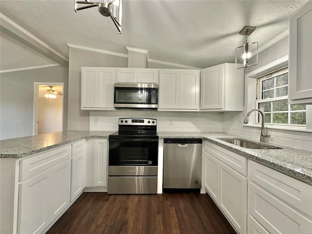 kitchen with sink, a textured ceiling, stainless steel appliances, vaulted ceiling, and white cabinets