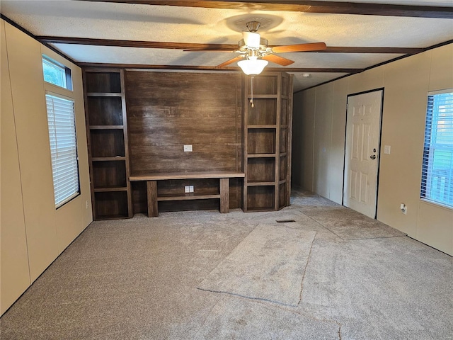 unfurnished living room featuring ceiling fan, a textured ceiling, wooden walls, and light colored carpet