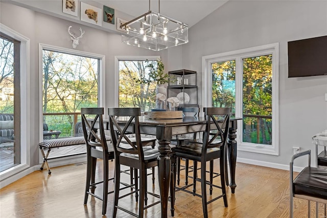 dining room featuring lofted ceiling, a chandelier, and light hardwood / wood-style floors