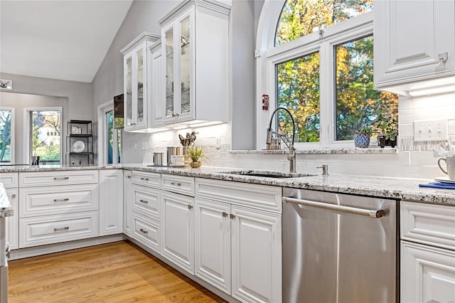 kitchen with sink, white cabinetry, light hardwood / wood-style floors, vaulted ceiling, and stainless steel dishwasher