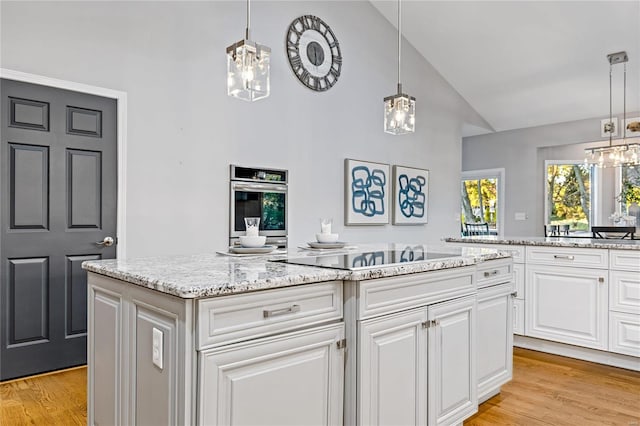 kitchen featuring an inviting chandelier, a center island, white cabinets, oven, and light wood-type flooring