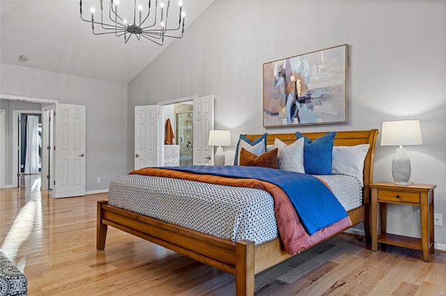 bedroom with an inviting chandelier, ensuite bath, high vaulted ceiling, and light hardwood / wood-style floors