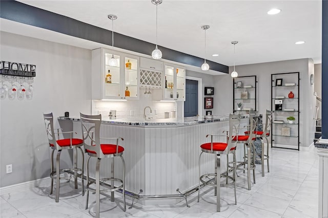 kitchen with a kitchen bar, kitchen peninsula, hanging light fixtures, and white cabinets