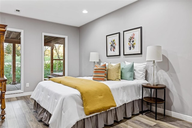 bedroom featuring multiple windows, wood-type flooring, and access to exterior