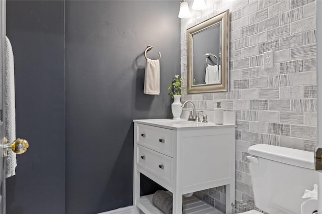 bathroom featuring vanity, tile walls, and toilet