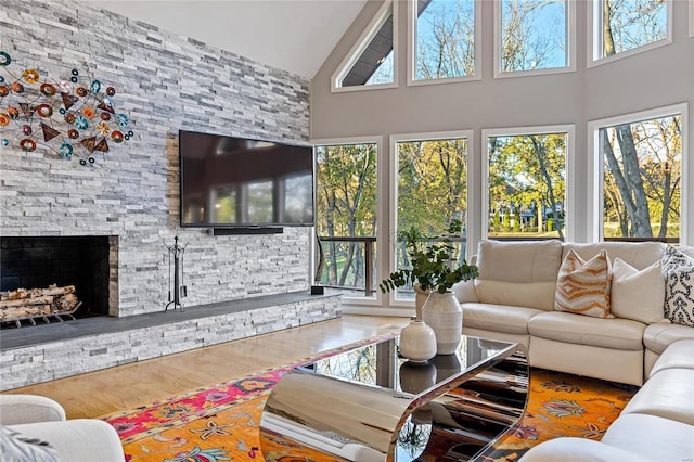 living room with wood-type flooring, a stone fireplace, and a wealth of natural light