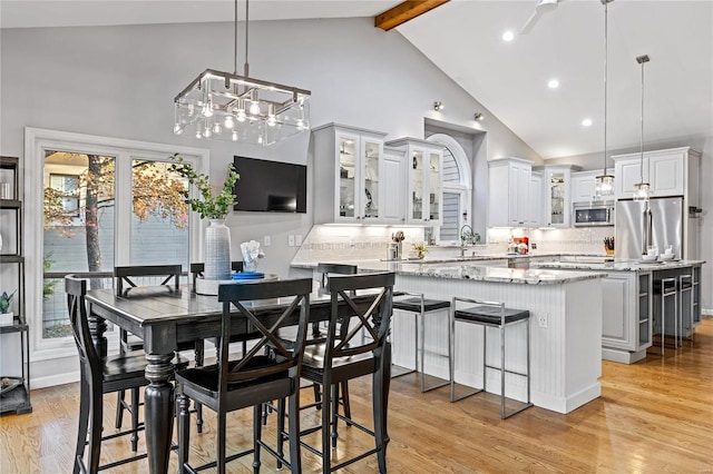 dining space with beamed ceiling, high vaulted ceiling, and light wood-type flooring