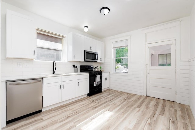 kitchen with decorative backsplash, sink, white cabinetry, appliances with stainless steel finishes, and light hardwood / wood-style floors