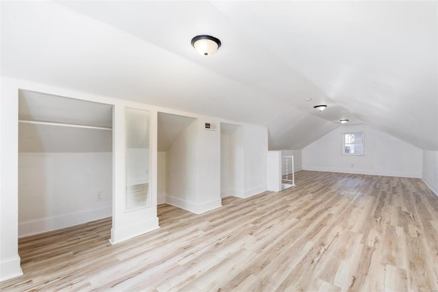 additional living space with light wood-type flooring and vaulted ceiling