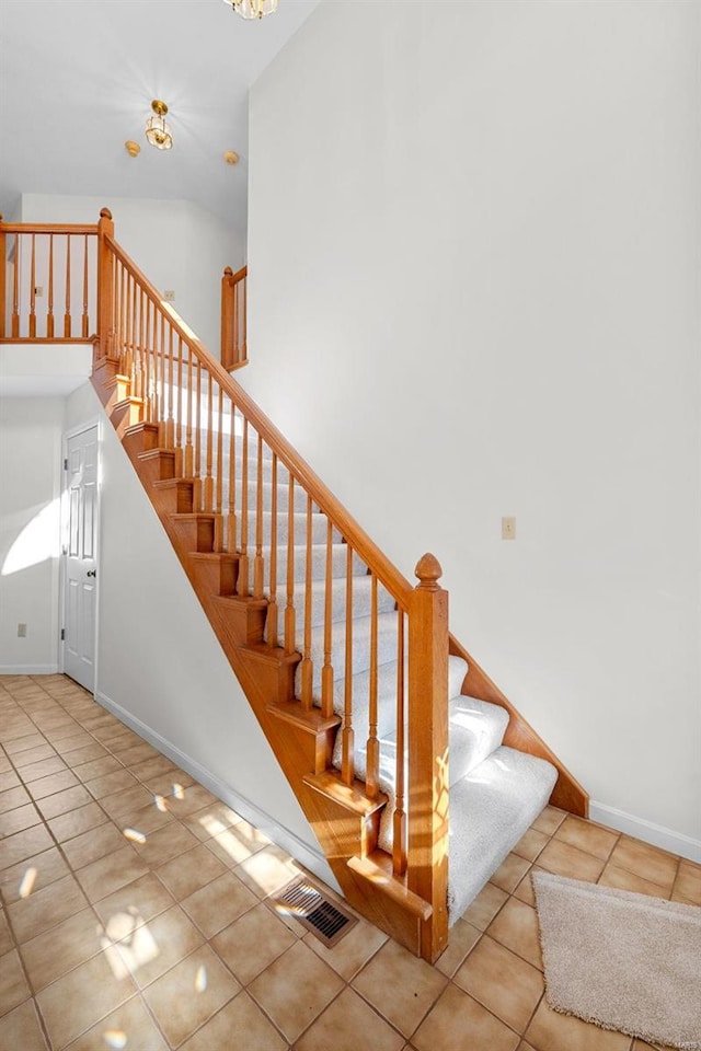 stairs with high vaulted ceiling, tile patterned floors, and a notable chandelier