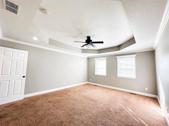 carpeted empty room with ornamental molding, a textured ceiling, and a tray ceiling