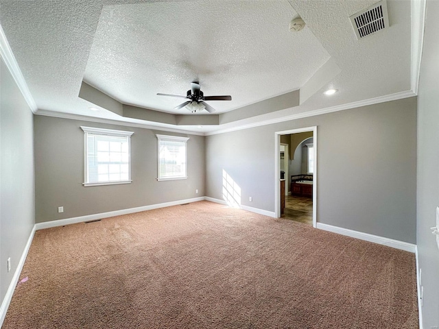 empty room featuring crown molding, a raised ceiling, a textured ceiling, carpet flooring, and ceiling fan