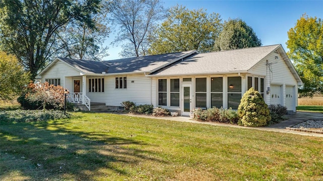 back of property featuring a sunroom, a lawn, and a garage