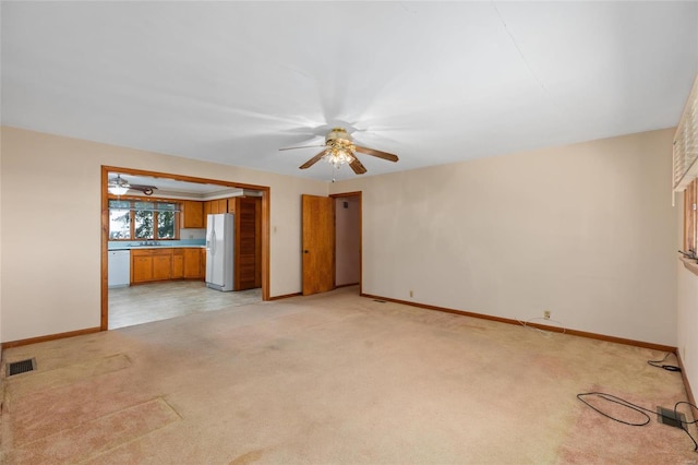 unfurnished living room with sink, light colored carpet, and ceiling fan