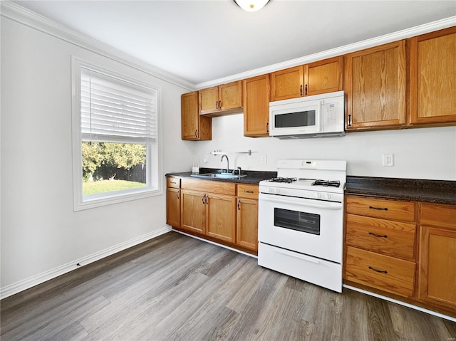 kitchen with crown molding, hardwood / wood-style flooring, sink, and white appliances