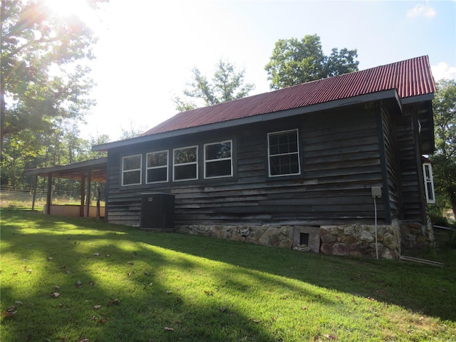 view of side of home with central AC and a yard