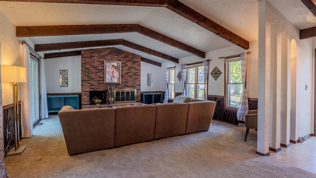 living room with vaulted ceiling with beams, a brick fireplace, light colored carpet, a textured ceiling, and wood walls