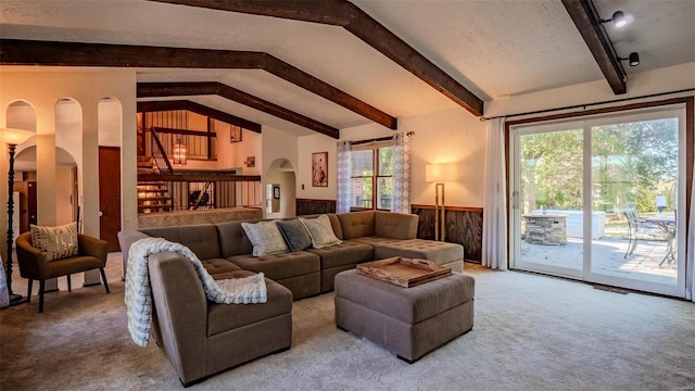 carpeted living room with lofted ceiling with beams, a textured ceiling, and wooden walls