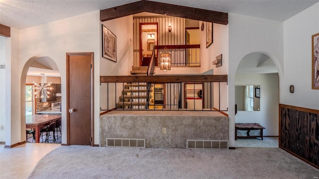 interior space featuring a chandelier, vaulted ceiling with beams, and a textured ceiling