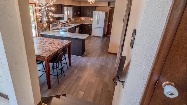 kitchen featuring sink, dark hardwood / wood-style flooring, stove, white fridge, and a notable chandelier