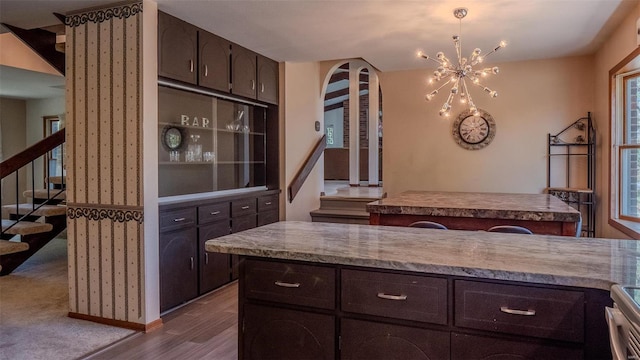 kitchen featuring a notable chandelier, dark brown cabinetry, light hardwood / wood-style flooring, and stainless steel range