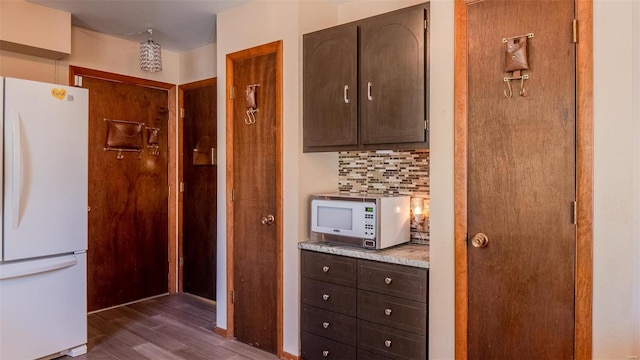 kitchen featuring dark wood-type flooring, dark brown cabinets, white appliances, and tasteful backsplash