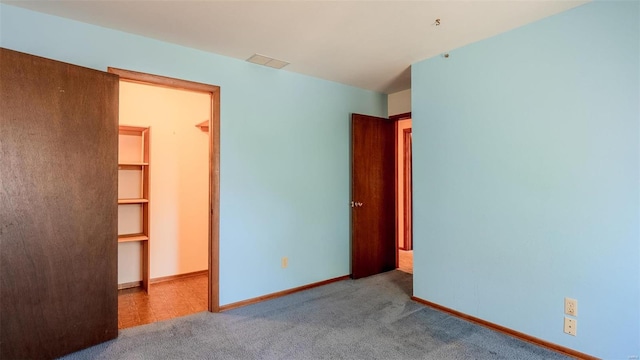 unfurnished bedroom with a closet, carpet floors, and a spacious closet