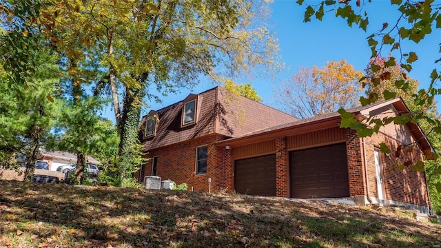 view of side of home with an attached garage, a shingled roof, and brick siding