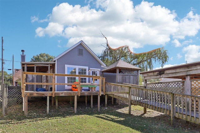 rear view of house featuring a yard and a wooden deck