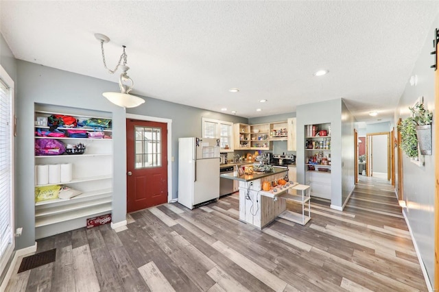 kitchen featuring light hardwood / wood-style flooring, dishwasher, decorative light fixtures, a breakfast bar area, and white refrigerator