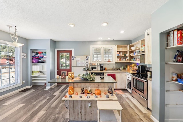 kitchen featuring light hardwood / wood-style flooring, hanging light fixtures, sink, a breakfast bar, and white appliances