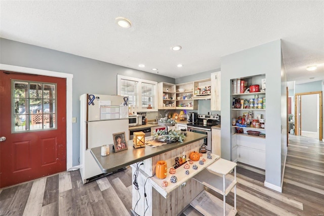 kitchen featuring stainless steel appliances, a textured ceiling, a breakfast bar, and hardwood / wood-style floors