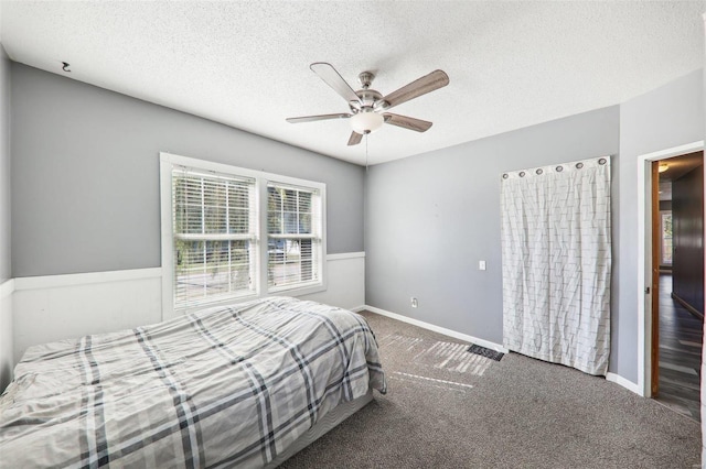 bedroom with ceiling fan, a textured ceiling, and dark carpet