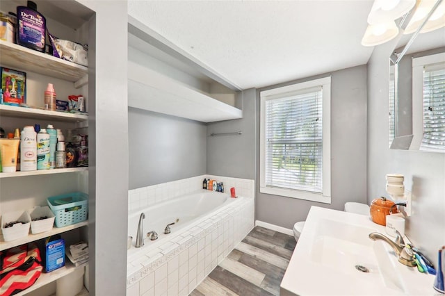 bathroom with toilet, a relaxing tiled tub, wood-type flooring, and a wealth of natural light