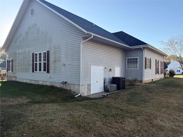 view of property exterior with central air condition unit and a yard