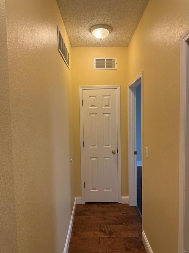 doorway to outside featuring dark wood-type flooring and a textured ceiling