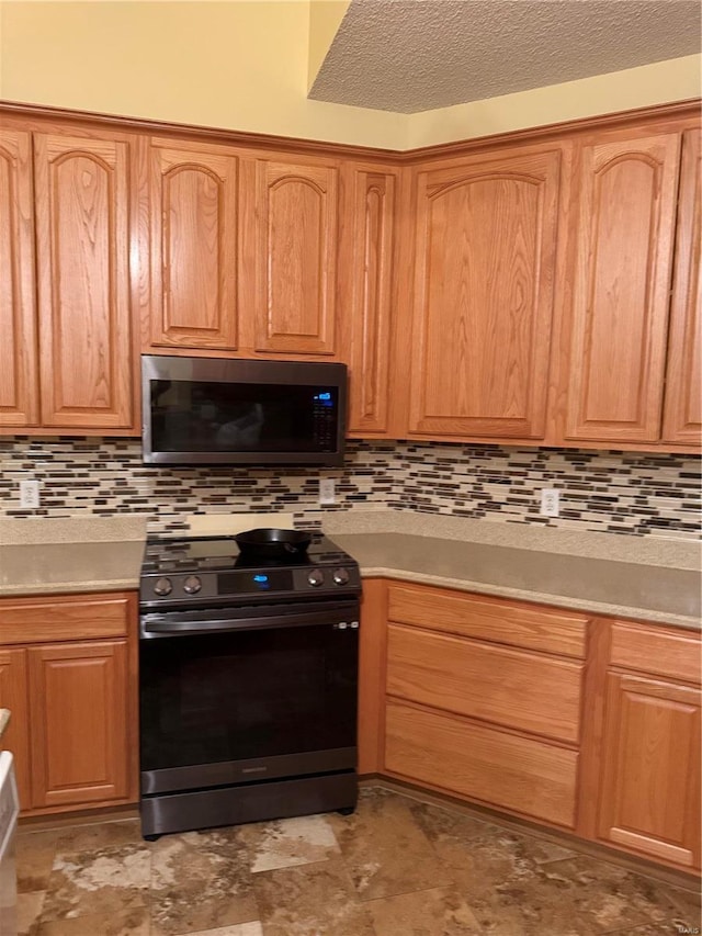 kitchen featuring decorative backsplash, black range, and a textured ceiling