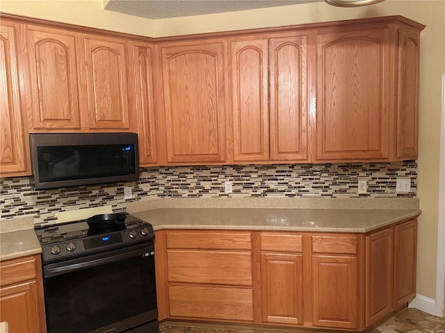 kitchen featuring backsplash, light stone countertops, and black range oven