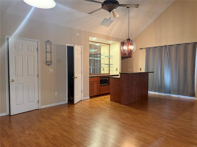 interior space featuring high vaulted ceiling, wood-type flooring, ceiling fan with notable chandelier, and pendant lighting