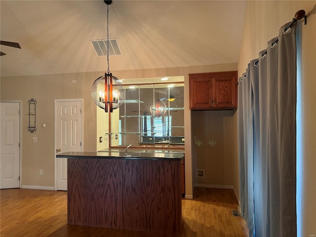 kitchen with lofted ceiling, hanging light fixtures, wood-type flooring, and ceiling fan with notable chandelier