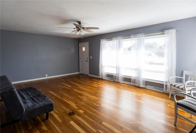 living area with dark wood-type flooring and ceiling fan