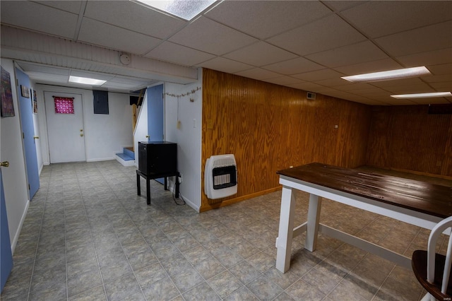 interior space with heating unit, wooden walls, and a drop ceiling