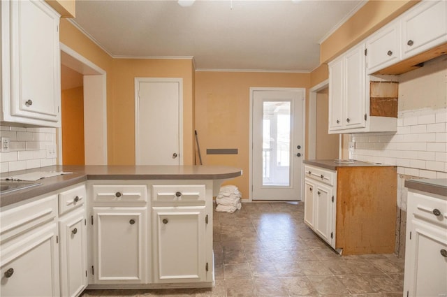 kitchen with crown molding, white cabinets, kitchen peninsula, and tasteful backsplash