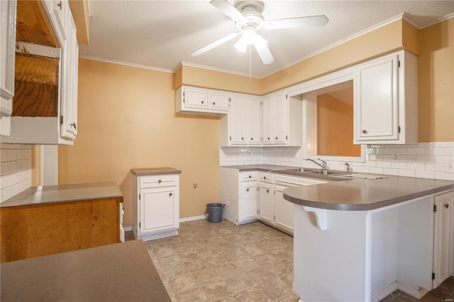 kitchen featuring decorative backsplash, kitchen peninsula, sink, white cabinets, and ceiling fan