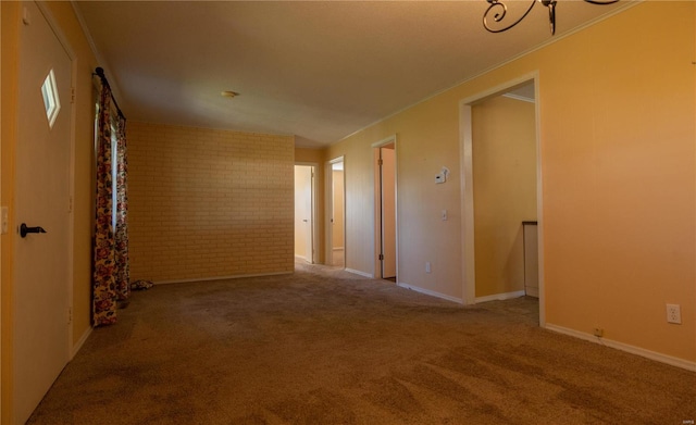 carpeted empty room featuring brick wall