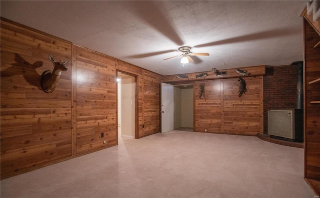 basement with wooden walls, carpet floors, a textured ceiling, and ceiling fan